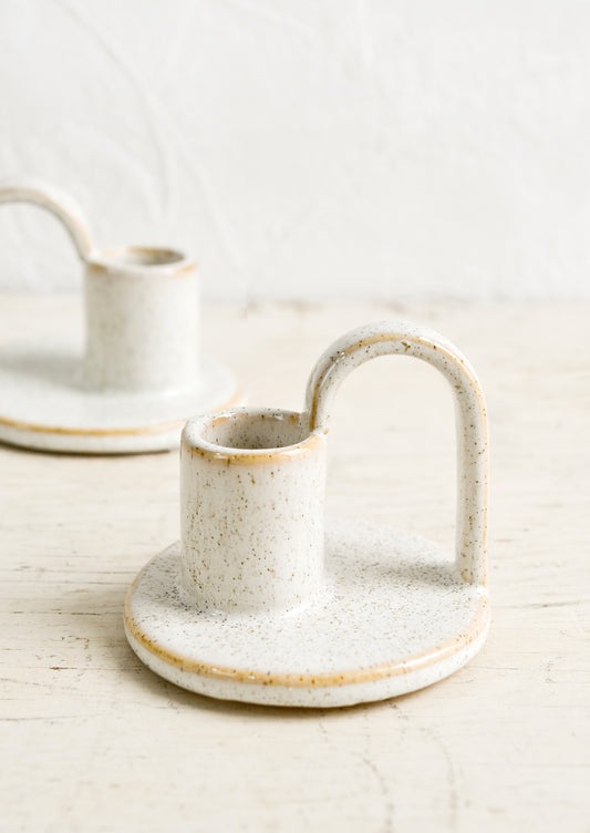 Ceramic taper holders with curved handle in speckled natural glaze.